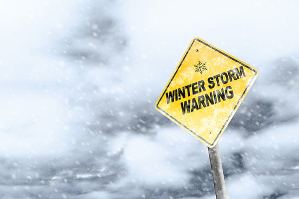 nor-easters Yellow caution sign that says "Winter Storm Warning" in front of storm clouds